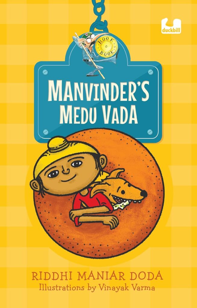 Book Cover
Manvinder's Medu Vada
Riddhi Maniar Doda
Illustrations by Vinayak Varma
Image of a boy and a dog emerging from the hole of a vada