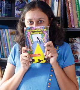 Varsha hiding half her face with the book The Prophecy of Rasphora